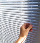 Hand closing white blinds